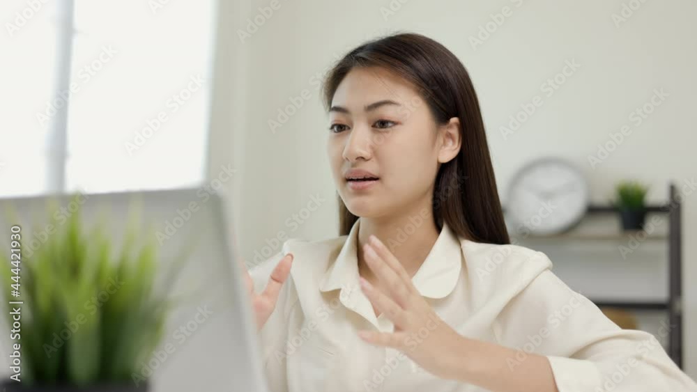 Young asian woman using laptop chatting video conference online sitting in living room at home. Business Woman looking at screen Meeting on social media live steam. Work, learning from home. Young asian woman using laptop chatting video conference online sitting in living room at home. Business Woman looking at screen Meeting on social media live steam. Work, learning from home.