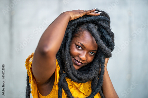 Beautiful young woman with dreadlocks in front of gray wall
 photo