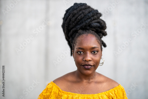 Beautiful young woman with dreadlocks in front of gray wall
 photo