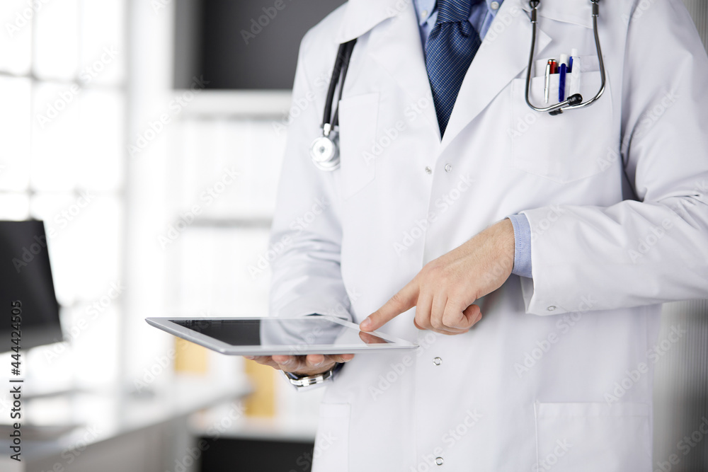 Male doctor using tablet computer in clinic, close-up. Perfect medical service in hospital Male doctor using tablet computer in clinic, close-up. Perfect medical service in hospital