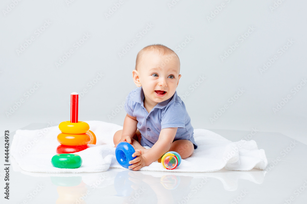 baby boy with a multi-colored pyramid is isolated on a white background; baby boy with a multi-colored pyramid is isolated on a white background;