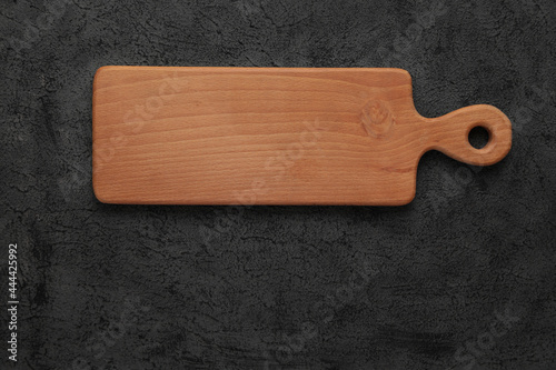 Brown wooden cutting board, on black stone table. Top view with copy space.. Rustic dishes