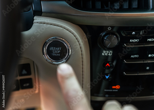Finger pressing button the start button, stop the engine in the luxury car. The man's finger is pressing down. Owner and dealership concept