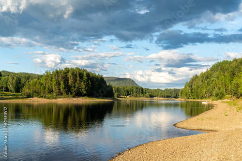 picturesque meandering river landscape with rocky river banks and reflections of forest and clouds in the water photo
