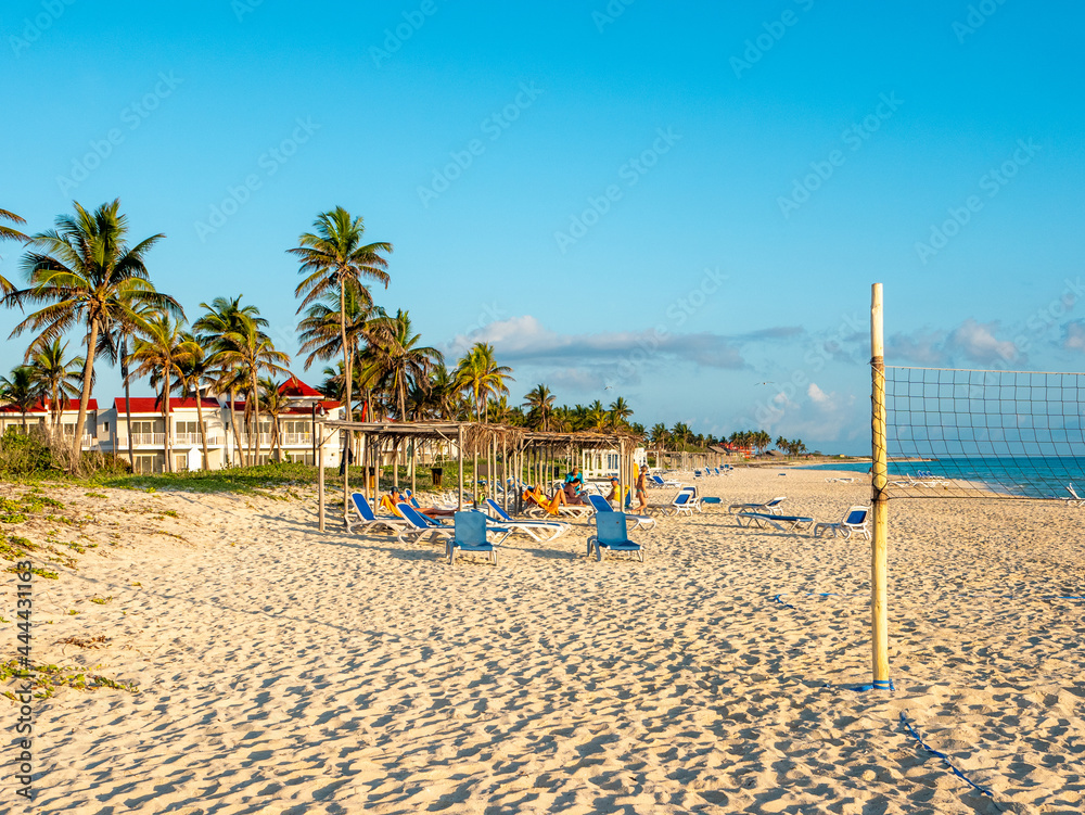 Cayo Coco, Cuba, 16 may 2021: Sandy beach of the hotel Tryp Cayo Coco with sun loungers and tall palm trees. People relax and sunbathe near the ocean on sun loungers.