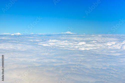 Clouds against blue sky view through an airplane window for a background.