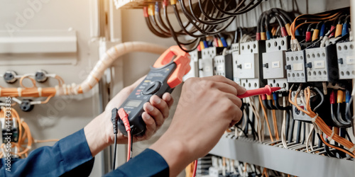 Foto Electrician engineer uses a multimeter to test the electrical installation and power line current in an electrical system control cabinet