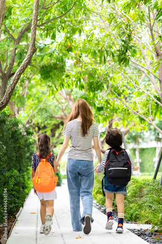 Parent and pupil of primary school go hand in hand. Woman and kids with backpack behind the back. Beginning of lessons.first day at school.Mother taking daughter to school photo