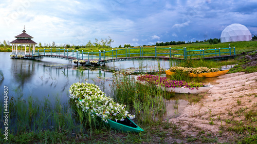A place for meditation. Gazebo, manor and boats with flowers by the lake. photo