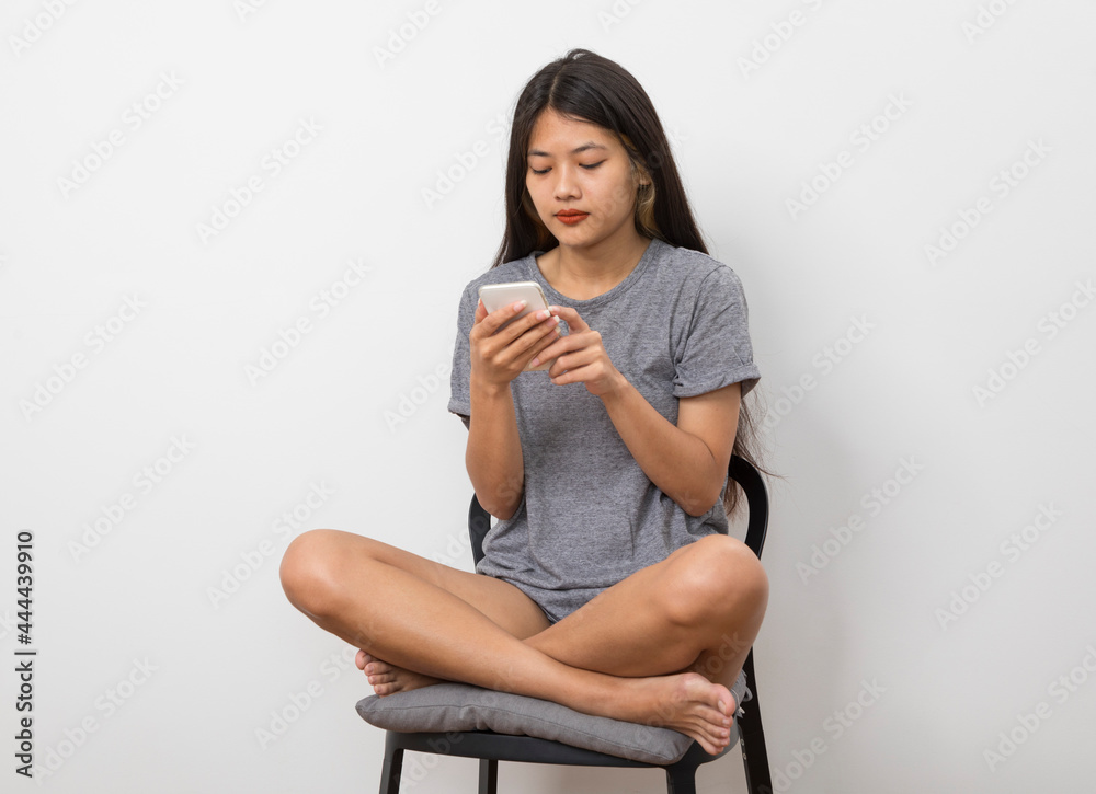Beautiful young Asian woman smiling sitting relax in the room, using smart phone on white background. Beautiful young Asian woman smiling sitting relax in the room, using smart phone on white background.