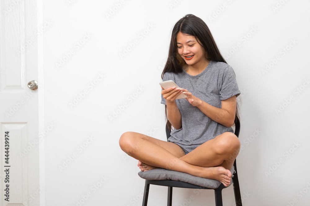 Beautiful young Asian woman smiling sitting relax in the room, using smart phone on white background. Beautiful young Asian woman smiling sitting relax in the room, using smart phone on white background.