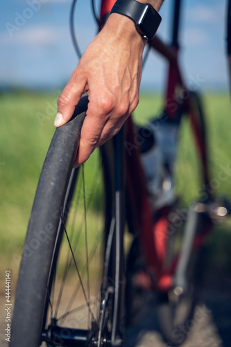 Vertical close up of a woman cyclist's hands checking the bike wheel tire pressure, before starting her bike route outdoor.