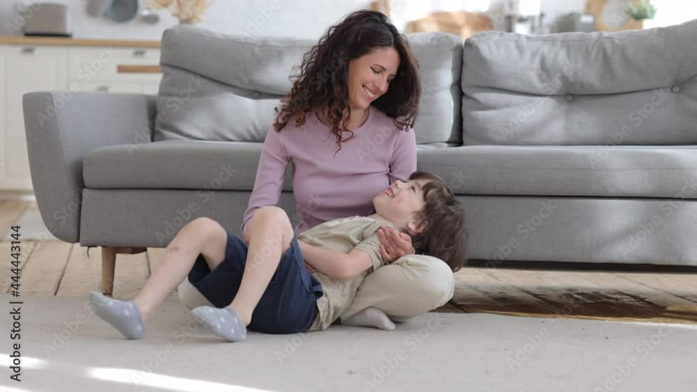 Overjoyed loving mom has fun with small son tickling boy sitting with kid on floor carpet in living room laughing. Cheerful caucasian woman mom or baby sitter enjoy funny playing with child at home Overjoyed loving mom has fun with small son tickling boy sitting with kid on floor carpet in living room laughing. Cheerful caucasian woman mom or baby sitter enjoy funny playing with child at home