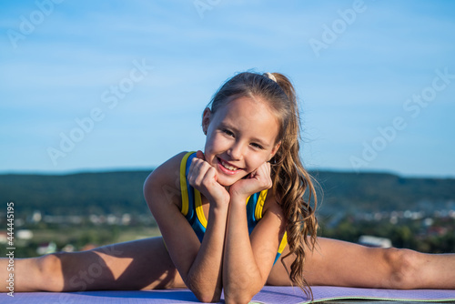 teen girl wear sportswear for training stretching on sky background, split