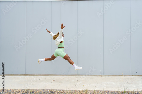 Side view of an african american woman jumping with legs spread and arms outstretched © carles