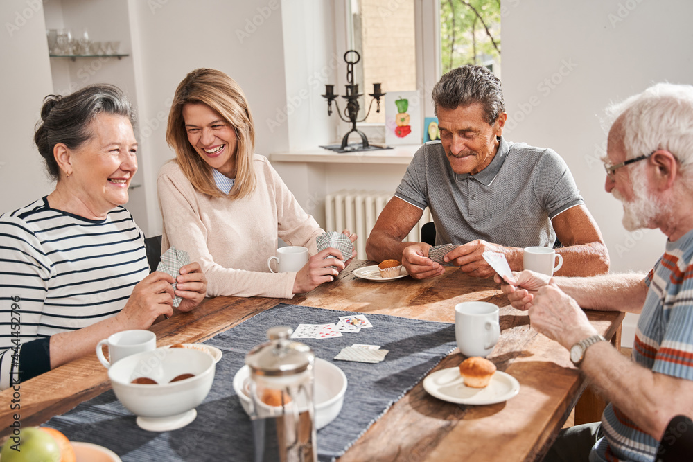Pensioners sitting at the table and playing at the cards with each other