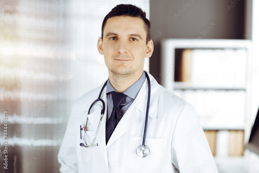 Male doctor standing straight in sunny clinic. Perfect medical service in hospital