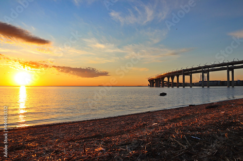 orange sunset over the river with a highway bridge