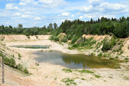 Small lakes in a quarry or canyon. Landscape with sandy hills. Sunny day and bright blue sky.