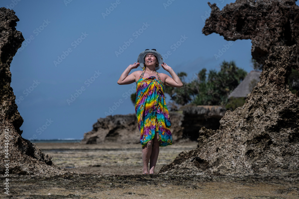 woman in a blue hat posing against the backdrop of corals and islands during low tide of the sea 
