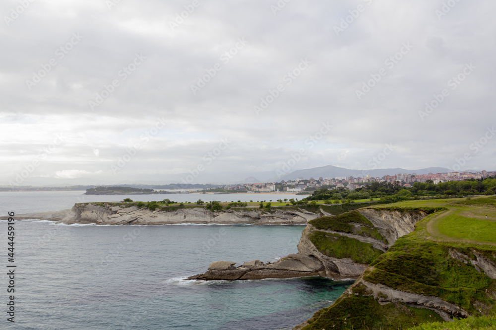 Sunset on a cliff facing the sea on a cloudy day with the city of Santander (Spain) in the background.  Selective focus. Copy space.