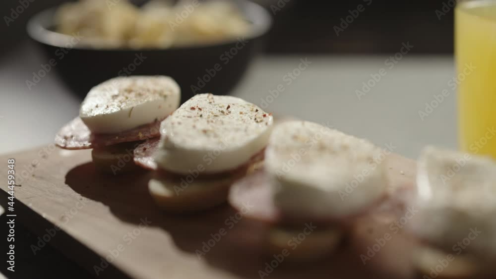 Slow motion handheld shot of small canapes with salami and mozzarella on baguette slices with pesto Slow motion handheld shot of small canapes with salami and mozzarella on baguette slices with pesto