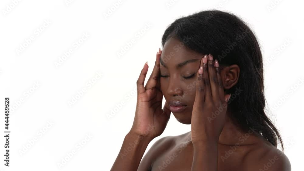Side view of an African woman, massaging her temples with her hands. Looking away from the camera, in distress, with closed eyes. White background. Side view of an African woman, massaging her temples with her hands. Looking away from the camera, in distress, with closed eyes. White background.