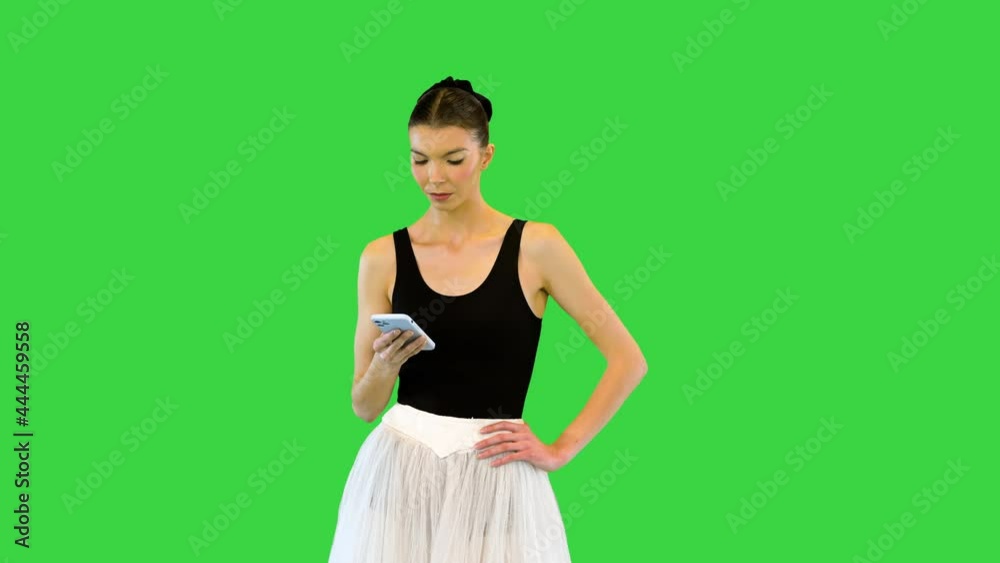 Tired ballerina with her smartphone on the break of training on a Green Screen, Chroma Key.