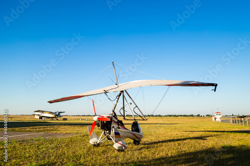 Motor hang glider standing on green grass at aerodrome, bright summer day