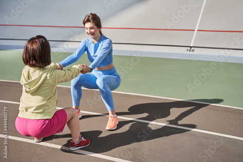 Midget woman squatting with her best friend at the stadium outdoor during the morning