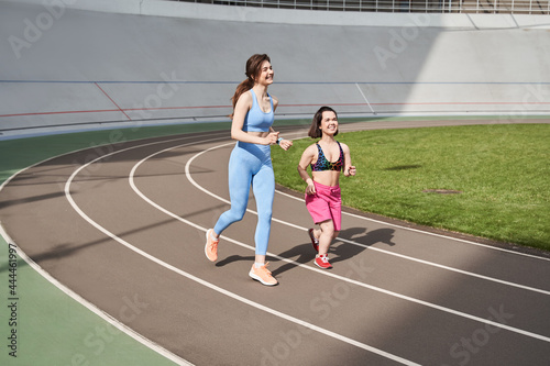 Girls jogging on running track in city stadium at the sunny morning