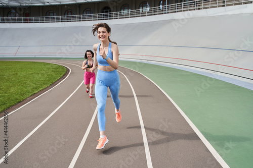 Two happy girls running one after another at the morning