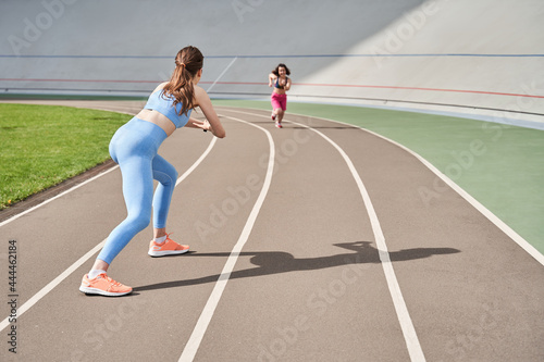 Girl waiting at the finish to her midget friend while she running at the stadium