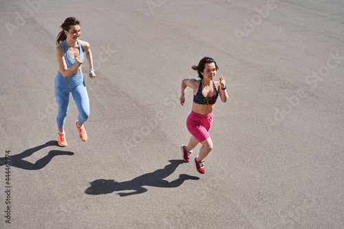 Two sporty girls jogging at the stadium at the morning during the workout