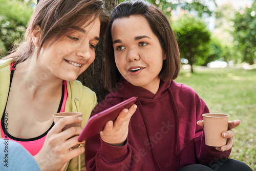 Best friends looking at the smartphone and singing songs at the nature photo