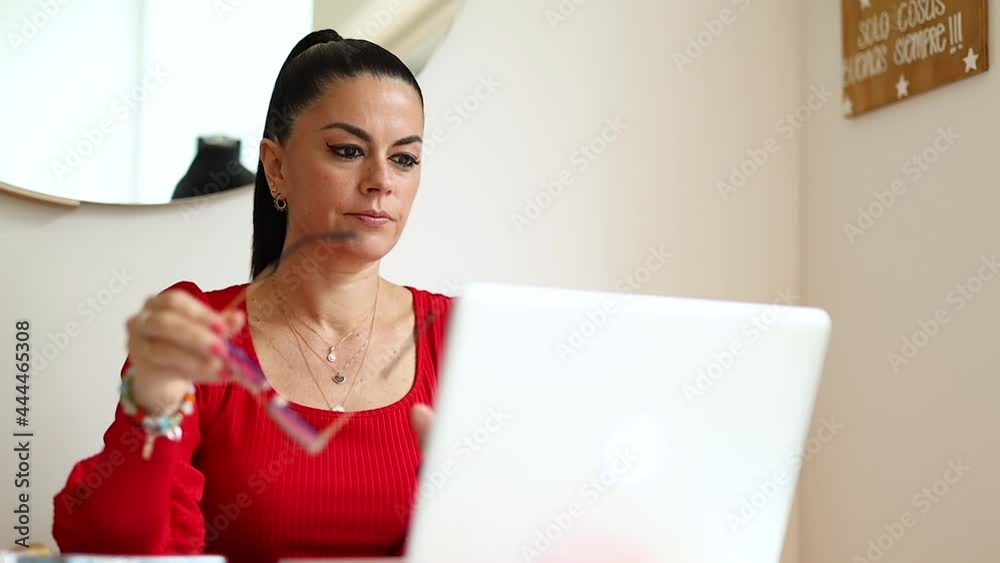 mujer latina senatada en la mesa de su hogar, haciendo negocios desde su laptop