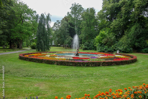 Springbrunnen in einem grünen Park mit viele im Kreis angeordneten Blumen. Zirkel Kreisverkehr ohne Straße nur auf grün mit Rasen und Blütenpracht und Wasserfontäne. photo