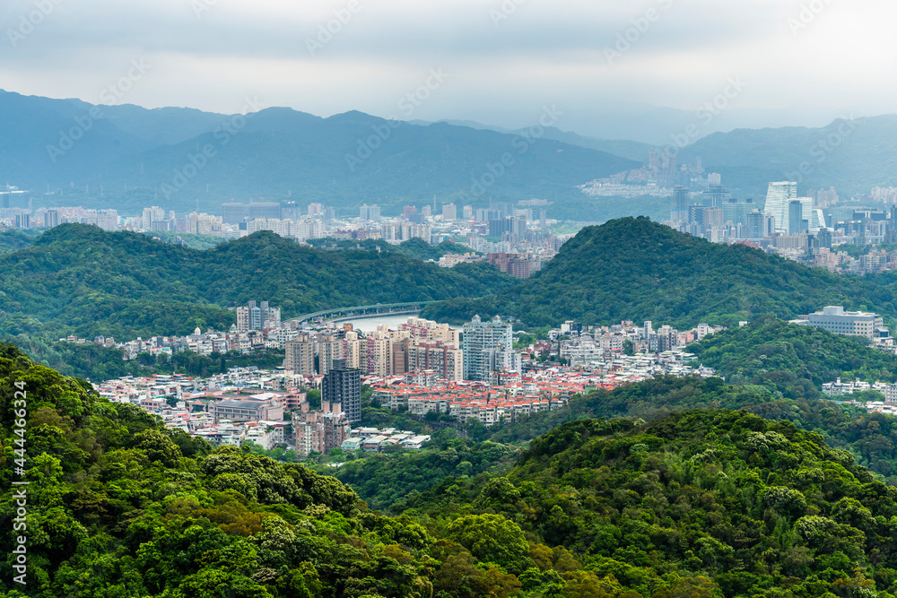 Overlooking the urban architectural landscape of the Neihu and Nangang in Taipei, Taiwan, surrounded by green forests and mountains.