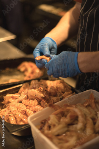 chef peeling shrimp with blue gloves