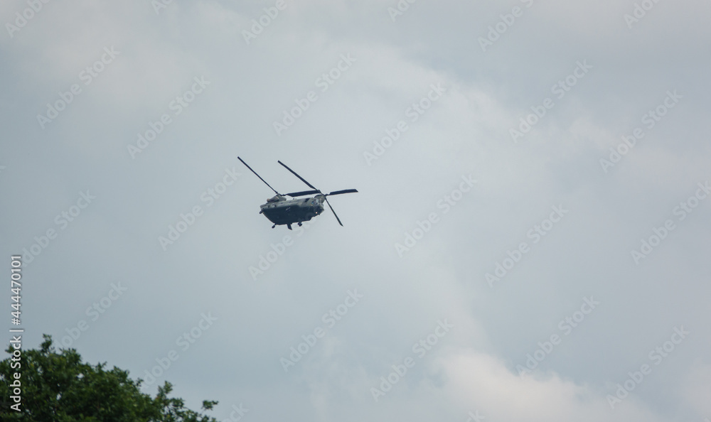 Fototapeta premium RAF Boeing Chinook UH-1 helicopter flying low in a cloudy blue grey and white summer sky