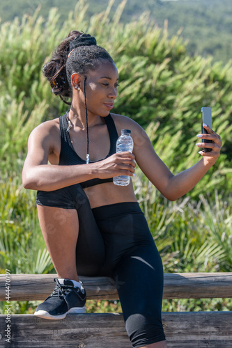 Fototapeta Naklejka Na Ścianę i Meble -  Afro american woman outdoors taking a photo of herself after exercising: Photography concept.