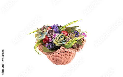 Flower arrangement of artificial flowers in a plastic wicker basket isolated on a white background.