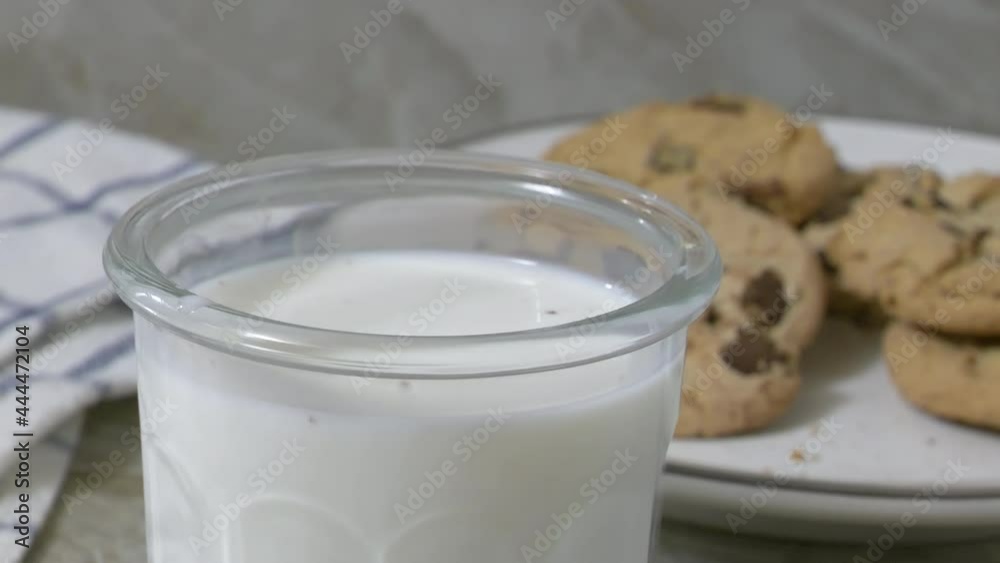 Dunking a piece of a chocolate chip cookie into a glass of milk slow motion
Dunking a piece of a chocolate chip cookie into a glass of milk slow motion