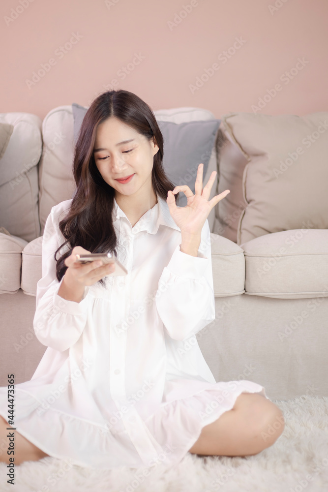 Happy teen girl checking social media holding smartphone and show OK sign at home Happy teen girl checking social media holding smartphone and show OK sign at home