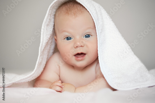 Close-up portrait of cute baby boy in white terry towel on white background. Bathing babies and restful sleep. funny child face..