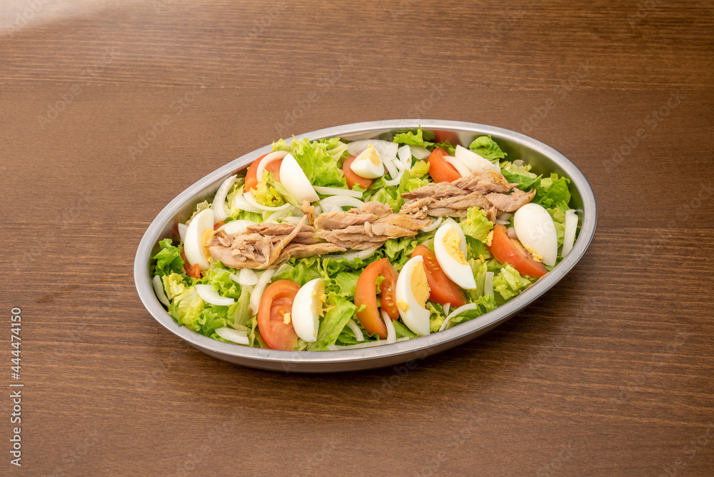 Metal salad tray to share with lots of iceberg lettuce, tomato and chopped boiled egg, slices of white onion and canned tuna on top. Metal salad tray to share with lots of iceberg lettuce, tomato and chopped boiled egg, slices of white onion and canned tuna on top.