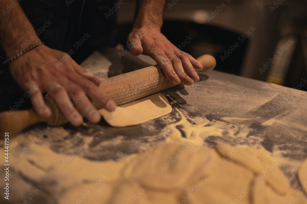 the cook rolls out the dough with a rolling pin. Table in flour