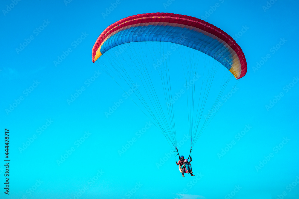 Doubles paragliding against a clear blue sky. A multi-colored papaplan flies in the clear sky closeup. Doubles paragliding against a clear blue sky. A multi-colored papaplan flies in the clear sky closeup.
