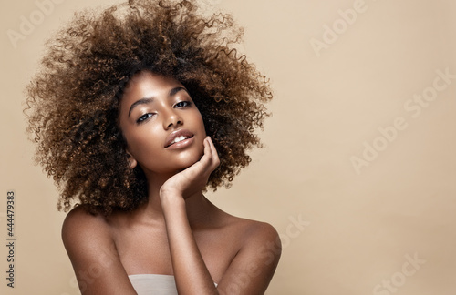 Beauty portrait of african american woman with clean healthy skin on beige background. Smiling dreamy beautiful afro girl.Curly black hair