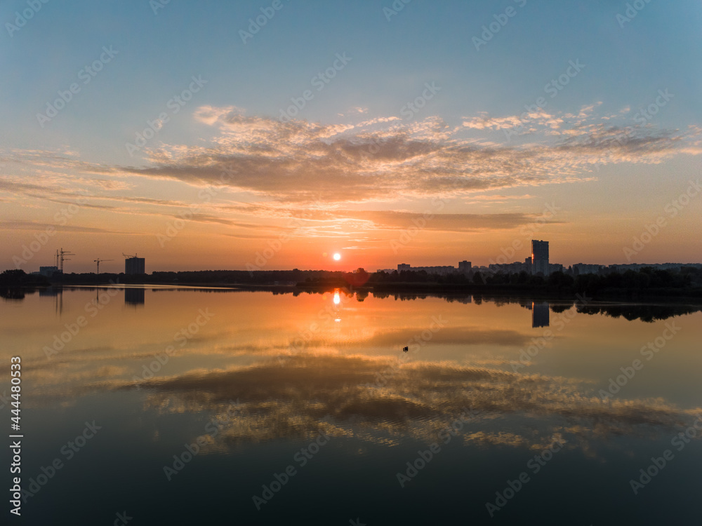 Scenic aerial sunrise with clouds reflecting in mirror water surface on wide river. Early morning, dawn in Kharkiv Zhuravlivskyy Hidropark from sky. Drone photography